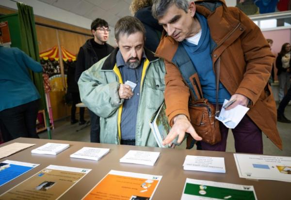 Un éducateur explique les règles pour voter lors d'un faux scrutin organisé pour des personnes en situation de handicap intellectuel, le 17 février 2026 à  Saint-Dié-des-Vosges
