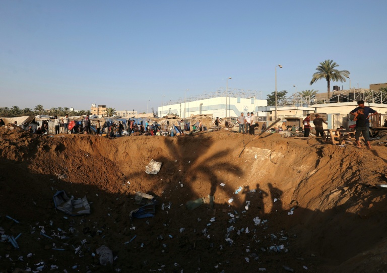 Des Palestiniens déplacés regardent un immense cratère à la suite d'une frappe aérienne israélienne qui a visé l'entrepôt de fournitures médicales de l'hôpital d'Al-Aqsa, à Deir al-Balah, dans le centre de la bande de Gaza, le 1er août 2026