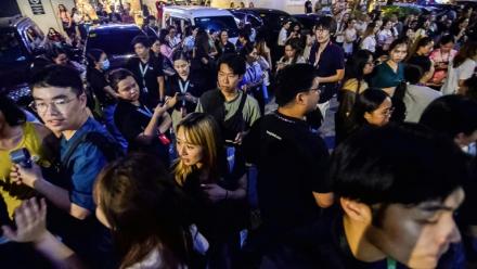 Les employés du centre d'appels surfent sur leurs téléphones portables alors qu'ils se rassemblent devant leur immeuble de bureaux après les secousses du tremblement de terre à Cebu, dans le centre des Philippines, le 30 septembre 2025