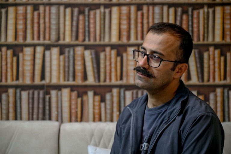 Farhad Sheikhi, un Kurde iranien qui a rejoint les manifestations antigouvernementales en 2022, montre des images des manifestations en Iran lors d'une interview à Souleimaniyeh, le 12 mars 2026 en Irak