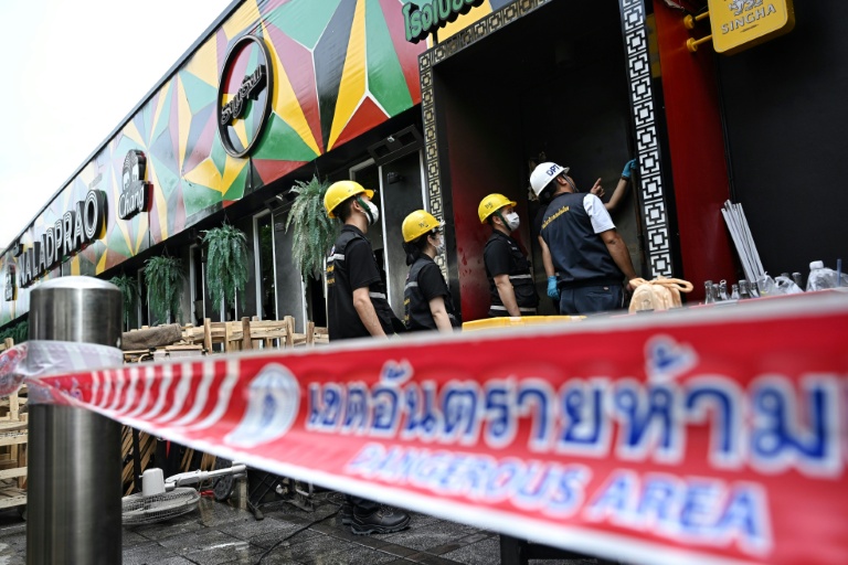 Des membres de la police scientifique inspectent les décombres calciné du bar-restaurant Rong Beer Na Lat Phrao, le 13 juillet 2026 à Bangkok, en Thaïlande