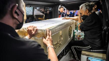 Une proche endeuillée accompagne le cercueil contenant la dépouille d'une victime de l'incendie d'un bar, dans un fourgon funéraire, le 14 juillet 2026 à l'hôpital général de la police de Bangkok, en Thaïlande