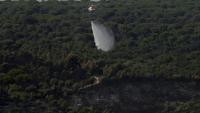 Un hélicoptère de lutte contre les incendies largue de l'eau pour rafraîchir une zone touchée par des feux de forêt à l'ouest de Madrid, le 28 juillet 2026