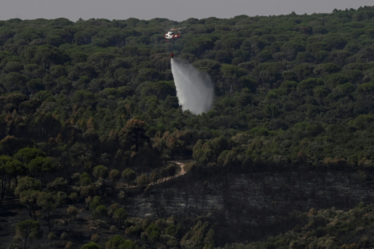 Un hélicoptère de lutte contre les incendies largue de l'eau pour rafraîchir une zone touchée par des feux de forêt à l'ouest de Madrid, le 28 juillet 2026