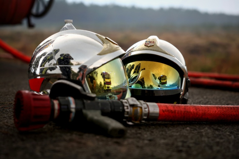 Deux casques de pompier et une lance à incendie gisent au sol alors qu'un incendie de forêt fait rage à Saint-Jean-d'Illac, à environ 30 km de Bordeaux, le 26 juillet 2026