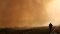 Un pompier marche sur une route à la lisière d'une zone en feu à Ares, le 26 juillet 2026, alors qu'un incendie de forêt ravage la forêt au nord du bassin d'Arcachon (Gironde) depuis le 22 juillet