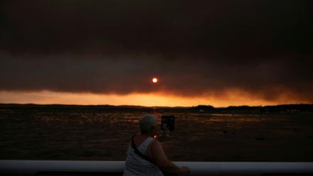 Une femme observe la fumée depuis la plage à Andernos-les-Bains lors d'un incendie dans la forêt de Lège-Cap-Ferret, dans le sud-ouest de la France, le 23 juillet 2026, alors qu'une partie de la zone voisine a été évacuée
