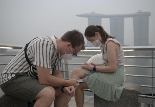 Des touristes portent des masques de protection contre les fumées générées par les incendies indonésiens, le 15 octobre 2026 à Singapour