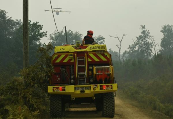 Un camion pompier survolé par un appui aérien le 15 août 2026 dans la forêt des Landes en flammes près de Luglon