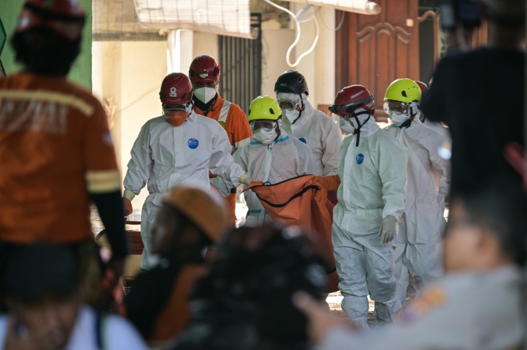 Des membres des équipes de secours transportent un sac mortuaire sur le site de l'effondrement de l'internat islamique Al Khoziny à Sidoarjo, dans l'est de Java, le 6 octobre 2025 en Indonésie