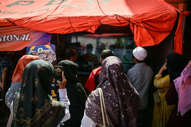 Des proches des élèves disparus regardent une retransmission en direct de l'opération de sauvetage près de l'internat islamique effondré d'Al Khoziny, à Sidoarjo, dans l'est de Java, le 6 octobre 2025 en Indonésie