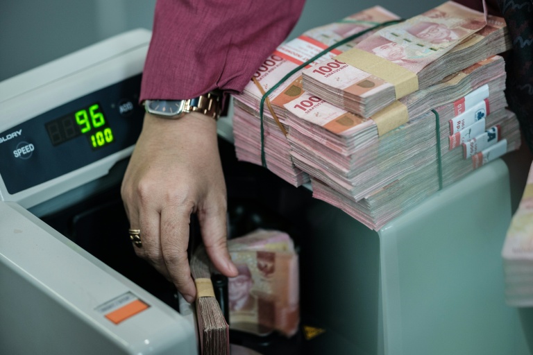 Un homme compte des billets de roupies dans un bureau de change à Jakarta en Indonésie le 4 juin 2026