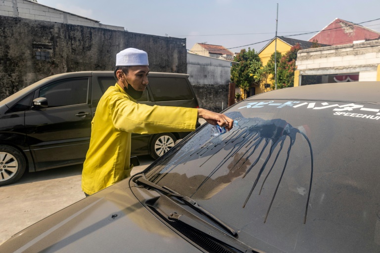 Un homme nettoie le pare-brise de sa voiture pour en retirer les cendres volcaniques après l'éruption du mont Anak Krakatoa à Bogor, dans la province de Java occidental, en Indonésie, le 6 septembre 2026