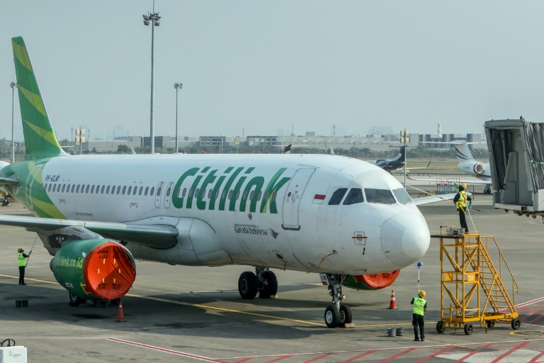 Des employés nettoient un Airbus A320 de la compagnie Citilink stationné sur le tarmac de l'aéroport Soekarno-Hatta, après la suspension des vols consécutive à l'éruption du volcan Anak Krakatau, le 7 septembre 2026 à Tangering, en Indonésie