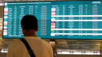 Un passager bloqué à l'aéroport international Soekarno-Hatta en raison de l'éruption du volcan Anak Krakatau, regarde un écran d'information sur les vols, le 7 septembre 2026 à Tangerang, en Indonésie