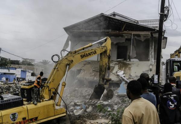 Un engin de chantier démolit des maisons à Kinshasa,, après que les autorités de la RDC ont décidé de démolir tous les bâtiments non autorisés dans les zones inondables, le 8 mai 2025 en RDC