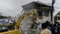 Un engin de chantier démolit des maisons à Kinshasa,, après que les autorités de la RDC ont décidé de démolir tous les bâtiments non autorisés dans les zones inondables, le 8 mai 2025 en RDC