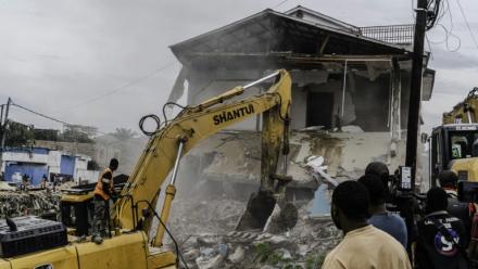 Un engin de chantier démolit des maisons à Kinshasa,, après que les autorités de la RDC ont décidé de démolir tous les bâtiments non autorisés dans les zones inondables, le 8 mai 2025 en RDC