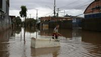 Un habitant utilise un réfrigérateur endommagé comme embarcation pour transporter des provisions dans une rue inondée de Porto Alegre, dans l'État de Rio Grande do Sul, au Brésil, le 26 mai 2024, pendant des inondations historiques dans le pays