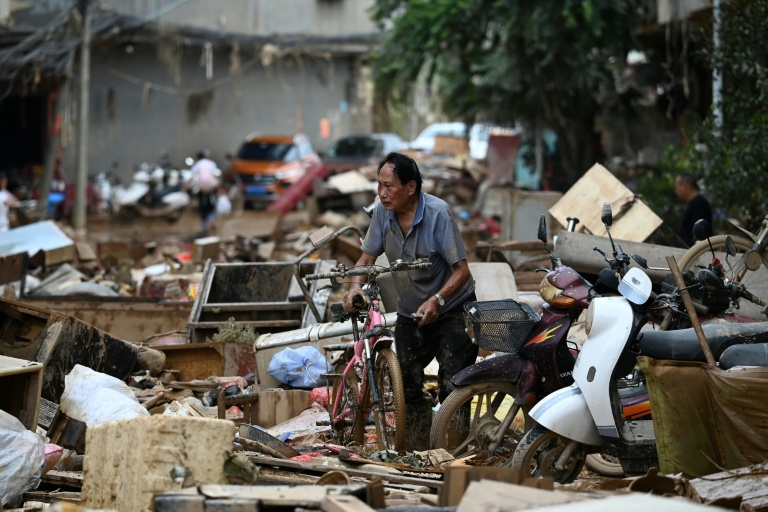 Un habitant pousse son vélo au milieu des débris dans une zone inondée après la rupture d'un réservoir près de Gantang, dans la région du Guangxi, le 9 juillet 2026 dans le sud-ouest de la Chine