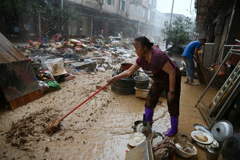 Une habitante repousse la boue dans une zone inondée après la rupture d'un réservoir près de Gantang, dans la région du Guangxi, le 9 juillet 2026 dans le sud-ouest de la Chine