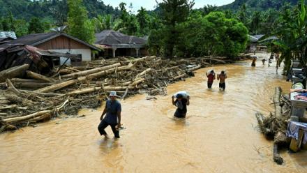 Des habitants progressent dans des eaux de crue au village de Tukka, en Indonésie, le 2 décembre 2025
