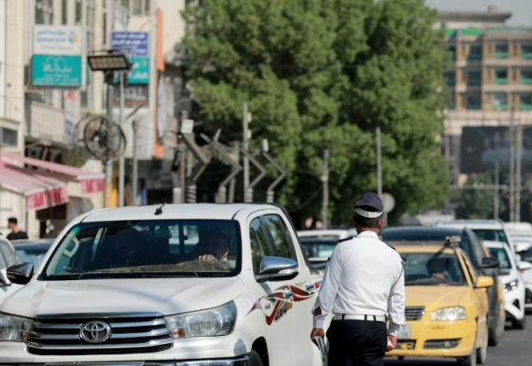 Un policier devant une file d'automobilistes qui attendent devant une station-service à Bagdad, le 5 septembre 2026 en Irak