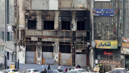 Des passants le 19 janvier 2026 devant un immeuble détruit lors des manifestations à Téhéran, en Iran