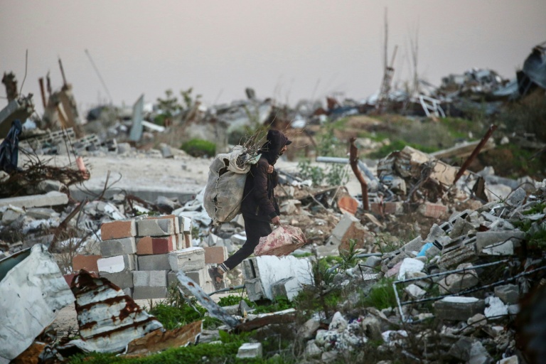 Un Palestinien transporte du bois à brûler dans les ruines du camp de réfugiés de Nousseirat, dans le centre de la bande de Gaza, le 31 décembre 2025