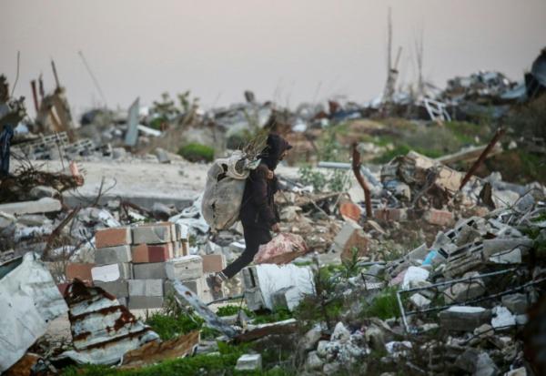 Un Palestinien transporte du bois à brûler dans les ruines du camp de réfugiés de Nousseirat, dans le centre de la bande de Gaza, le 31 décembre 2025