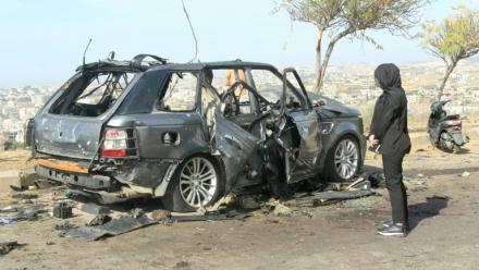 Une femme regarde le 2 novembre 2025 la carcasse d'une voiture, visée la veille par une frappe israélienne ayant tué ses occupants, dans dans le sud du Liban dans le district de Nabatiyeh