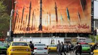 Des automobilistes passent devant un panneau d'affichage représentant des missiles balistiques iraniens, dans le centre de Téhéran, le 15 avril 2024