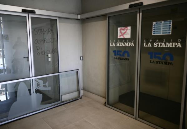 Un graffiti "La Stampa complice du génocide"  (g) devant les rédactions des journaux La Stampa et Repubblica lors d'une manifestation pour la libération de Mohamed Shahin, le 28 novembre 2025 à Turin 