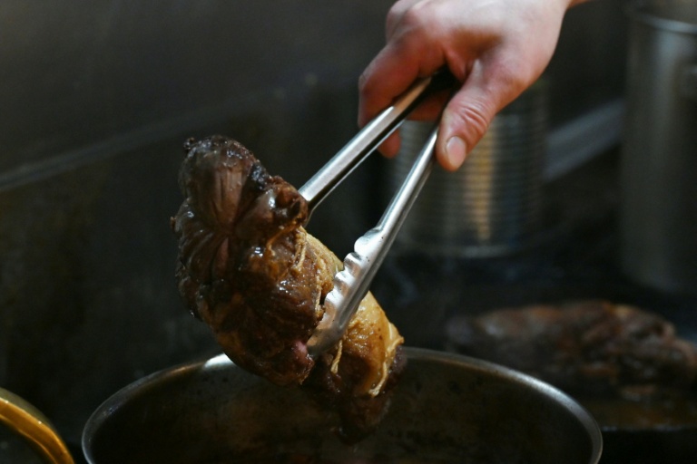 Le chef Kiyoshi Fujimoto met un morceau de viande d'ours dans une marmite pour les clients de son restaurant à Sapporo, dans la préfecture d'Hokkaido, le 9 décembre 2025 au nord du Japon
