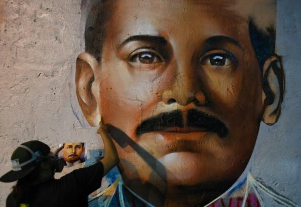 Le graffeur Wolfgang Salazar, alias Badsura, met la touche finale à un portrait du médecin vénézuélien Jose Gregorio Hernandez sur un mur de Caracas, le 27 avril 2021