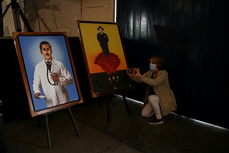 Une femme prend une photo de portraits du médecin vénézuélien Jose Gregorio Hernandez, installées dans la chapelle où a eu lieu sa béatification, à Caracas le 28 avril 2021