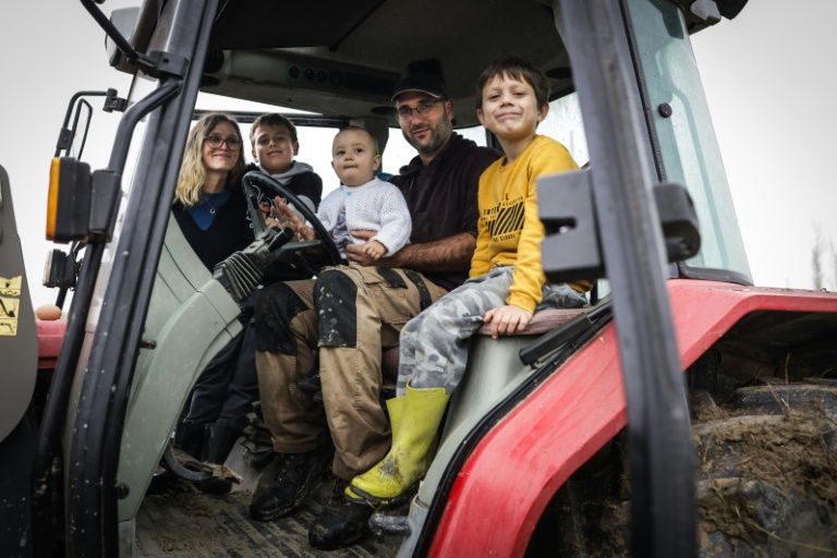 L'agriculteur Jérôme Caze, sa femme Sandra (g) et leurs trois enfants, Nino, Elie et Lialas, dans la cabine du tracteur dans leur ferme à Meilhan-sur-Garonne, le 24 octobre 2024 dans le Lot-et-Garonne