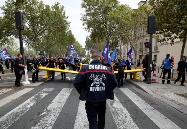 Un pompier portant une inscription "En grève" participe à une manifestation organisée par une large coalition de syndicats, à Paris, le 28 septembre 2026