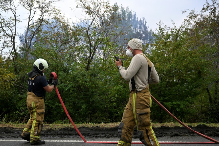 Des pompiers manœuvrent des lances pour lutter contre un incendie dans la réserve naturelle des Hautes Fagnes près de Waimes, dans l'est de la Belgique, le 17 août 2026