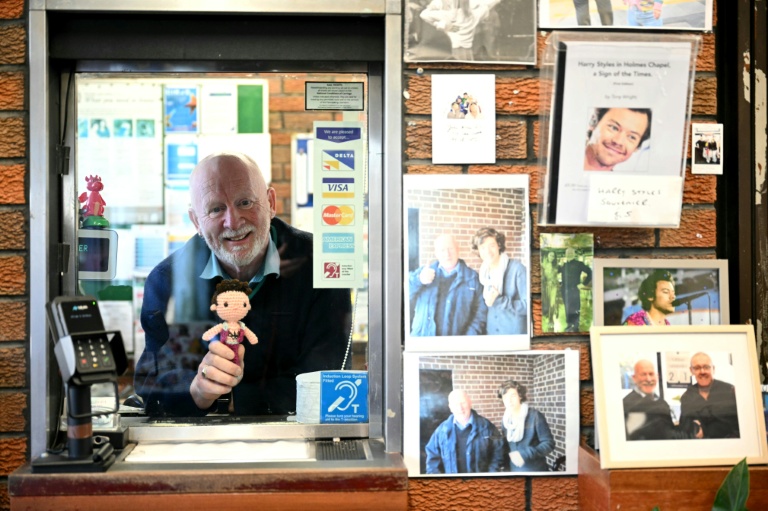 Le chef de gare Graham Blake tient une poupée à l'effigie de Harry Styles, entouré d'images du chanteur, en gare de Holmes Chapel, dans le nord-ouest de l’Angleterre, le 4 mars 2026 