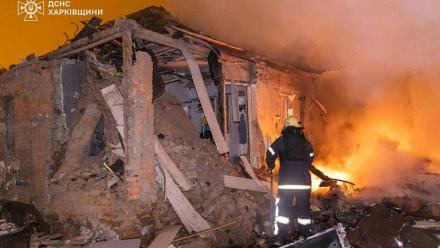 Photo diffusée le 26 février 2026 par le Service ukrainien des situations d'urgence montrant un pompier éteignant un incendie dans une maison endommagée après une attaque russe à Kharkiv