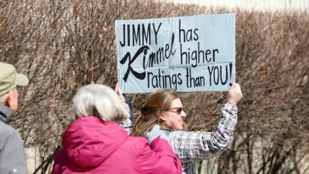 Une personne brandit une pancarte sur laquelle est écrit "Jimmy Kimmel a de meilleures audiences que toi" à Chicago lors d'une journée nationale de protestation contre le président américain Donald Trump, le 28 mars 2026