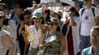 Des touristes avec des éventails devant la cathédrale Notre-Dame, le 16 août 2025 à Paris