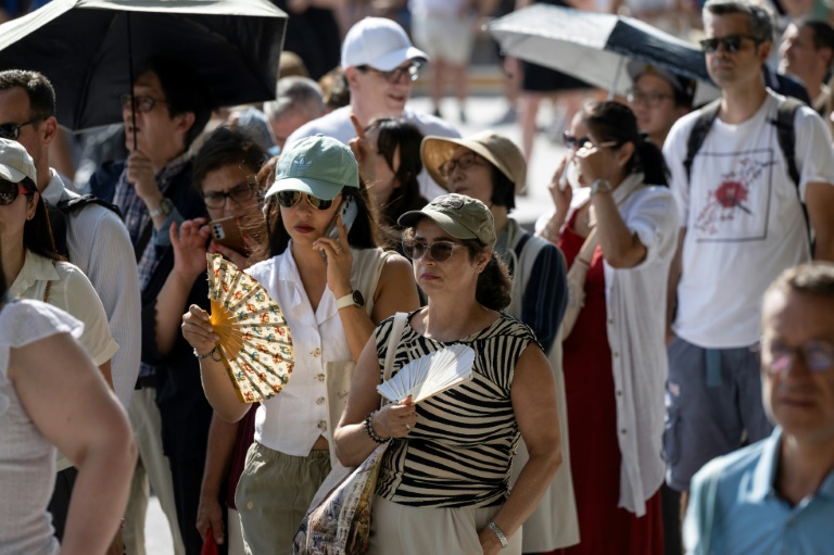 Des touristes avec des éventails devant la cathédrale Notre-Dame, le 16 août 2025 à Paris