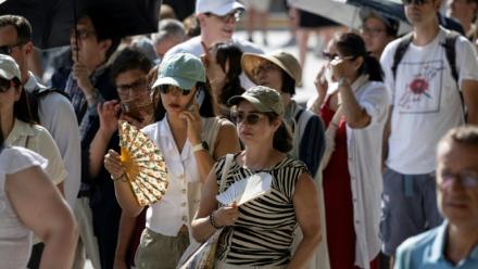 Des touristes avec des éventails devant la cathédrale Notre-Dame, le 16 août 2025 à Paris