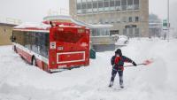 Un chauffeur de bus déneige une route alors que son bus est bloqué à cause de la neige à Toronto, au Canada le 17 janvier 2022