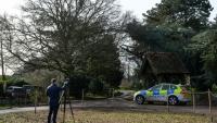 Un journaliste et un véhicule de police à l'entrée de Wood Farm, sur le domaine de Sandringham, appartenant à la famille royale britannique, en Angleterre, le 22 février 2026