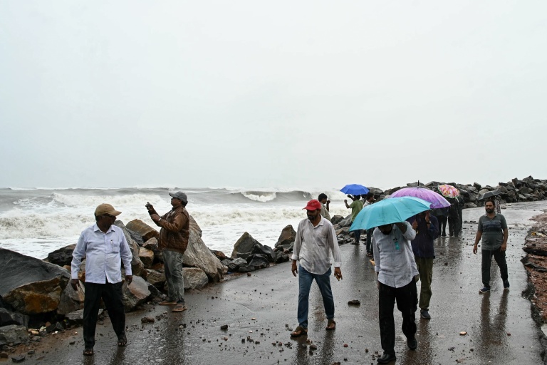 Des passants le long de la côte du golfe du Bengale, à Kakinada, en Inde, le 27 octobre 2026, avant le passage attendu du cyclone Arnab