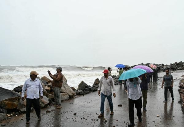 Des passants le long de la côte du golfe du Bengale, à Kakinada, en Inde, le 27 octobre 2026, avant le passage attendu du cyclone Arnab