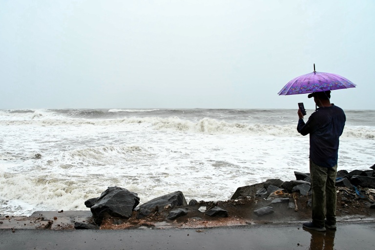 Un homme photographie la mer démontée le long de la côte du golfe du Bengale, à Kakinada, en Inde, le 27 octobre 2026, avant le passage attendu du cyclone Arnab